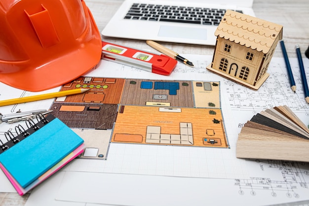 Hausprojektplan mit Arbeitswerkzeugen und Helm auf dem Schreibtisch