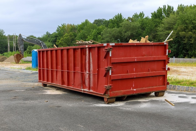 Hausrenovierung wartet einen beladenen Müllcontainer in der Nähe einer Baustelle