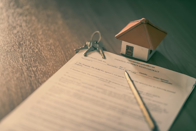 Hausschlüssel auf dem Mietvertrag oder den Kaufhausverträgen mit dem Immobilienhintergrund.