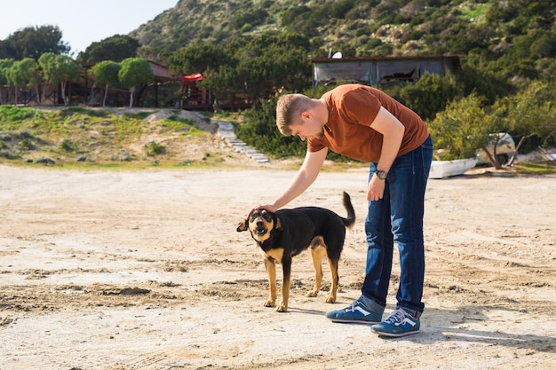 Haustier-, Haustier-, Jahreszeit- und Menschenkonzept - glücklicher Mann mit seinem Hund, der draußen geht.