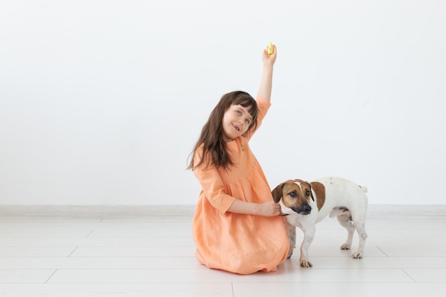 Haustier-, Kinder- und Hundekonzept - kleines Mädchen im Kleid, das mit Welpen spielt.