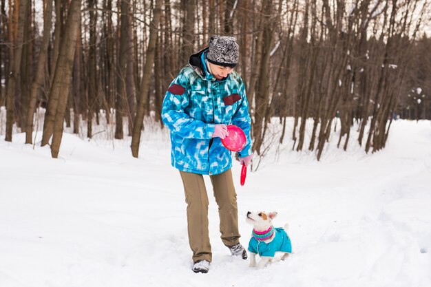 Haustierbesitzer und Winterkonzept - Frau mittleren Alters, die mit ihrem Jack Russell Terrier-Hund im Schnee spielt