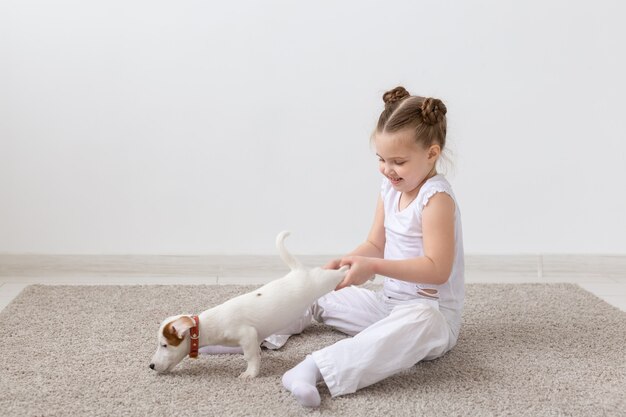 Haustierkinder und Tierkonzeptkindmädchen, das einen Welpen durch die Pfoten hält