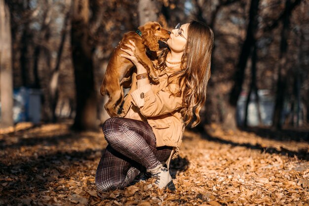 Foto haustierliebe niedlicher englischer cockerspaniel-welpe in den händen des besitzers im herbstpark frau geht mit kleinem englischen cockerspaniel-welpen im herbstlichen naturhintergrund spazieren