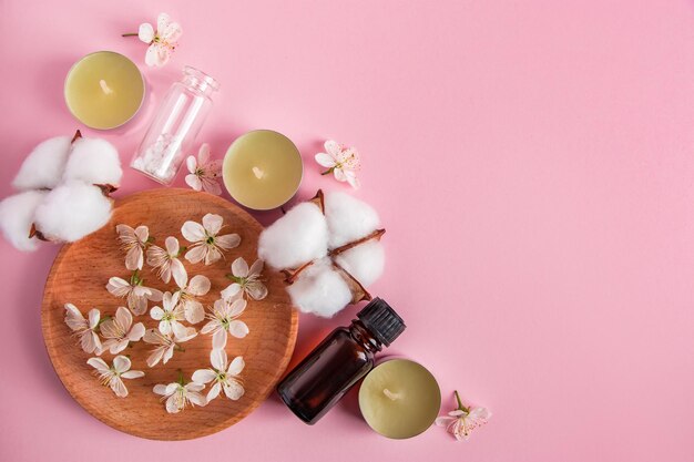 Hautpflege-, Spa- und Aromatherapie-Konzept. Naturkosmetikprodukte auf rosa Hintergrund. Aromakerzen und Blumen für Entspannung und Yoga. Platz für Ihren Text.