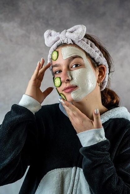 Hautpflege und Behandlung für junge Kundinnen im Spa mit Ton-Gesichtsmaske und Gurke. Schönheits- und Kosmetikkonzept