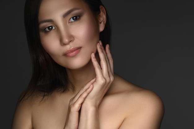 Hautpflege und Wellness. Porträt der jungen und schönen asiatischen Frau auf dunkelgrauem Hintergrund