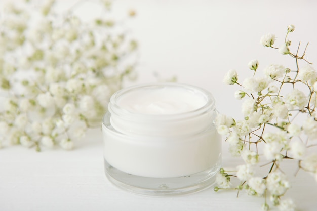 Hautpflegecreme und Blumen auf dem Tisch Kosmetik für die Hautpflege