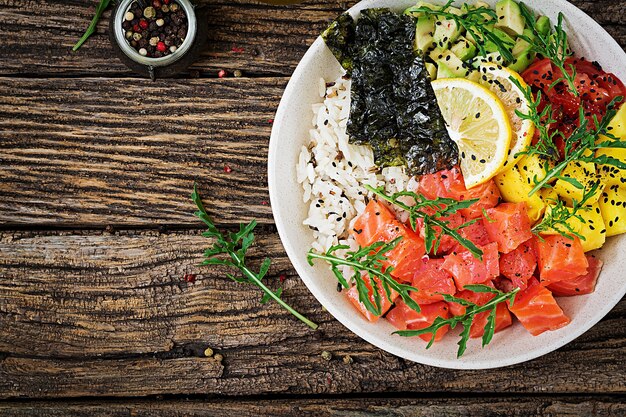 Hawaiian Lachs Fisch Poke Bowl mit Reis, Avocado, Mango, Tomate, Sesam und Algen.