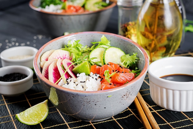 Hawaiian Lachs Fisch Poke Bowl mit Reis, Gurke, Rettich, Sesam und Limette. Buddha Schüssel. Diätessen.