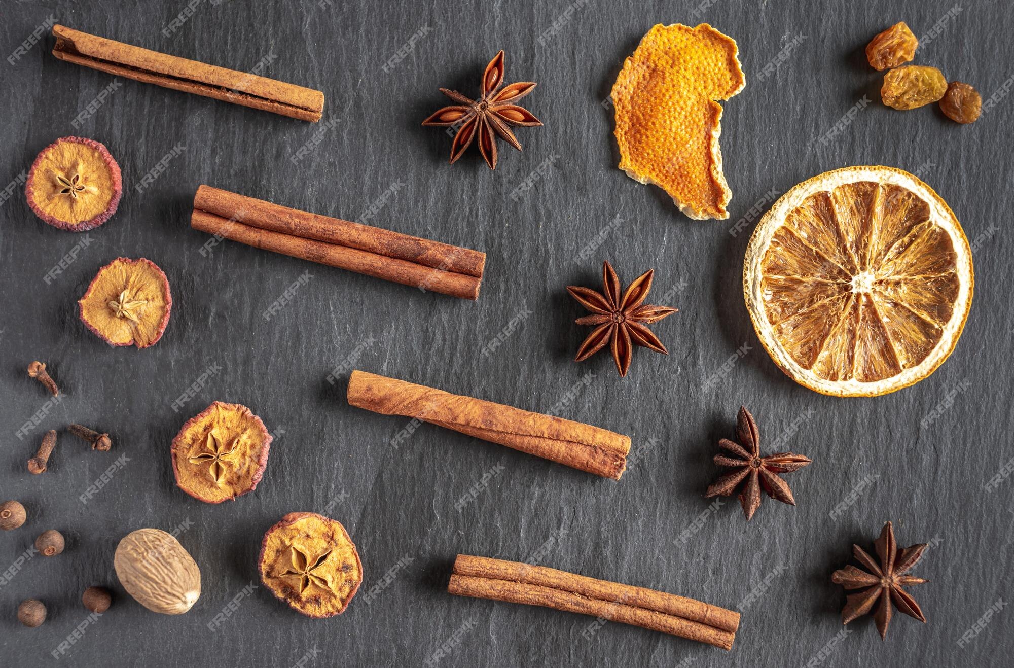 Hay círculos secos de canela naranja, estrellas de anís estrellado, nuez  moscada, pimienta sobre un fondo negro. ingredientes para vino caliente,  una receta para hacer una bebida tradicional de calentamiento. | Foto