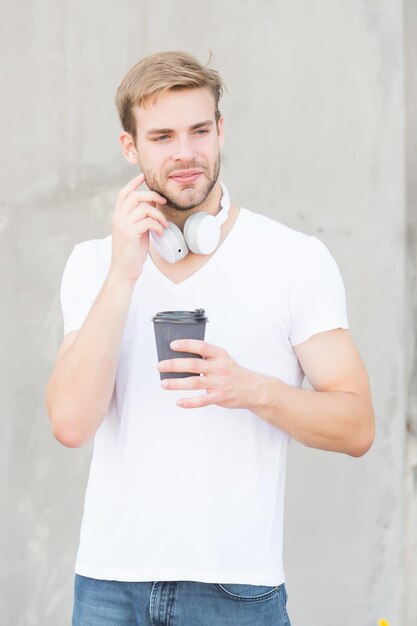 Hay docenas de bebidas que puedes elegir Un hombre guapo bebe café para llevar en un vaso de papel Concepto de cafetería Cafetería Chico tranquilo y pacífico disfruta de café recién hecho Latte perfecto Cantidad diaria de cafeína