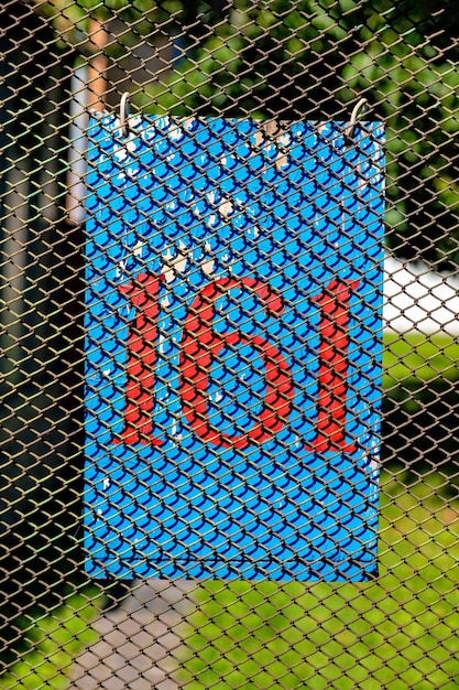 Foto hay un letrero azul con el número 161 en rojo colgado en la valla