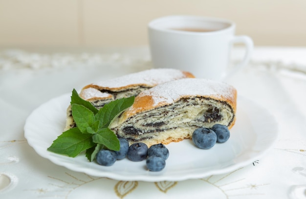 Hay un plato de pastel de semillas de amapola en la mesa y una taza de té al lado.