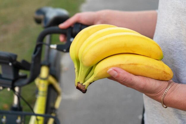 Hay un ramo de plátanos en sus manos una mujer está sosteniendo la fruta