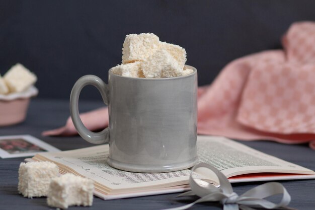 Hay una taza en la mesa llena de dulces hechos a mano.