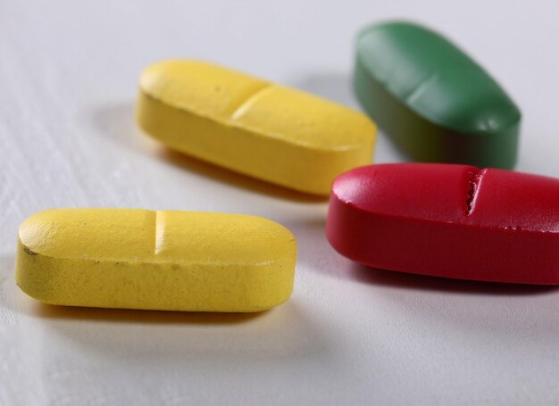 Hay tres pastillas sobre una mesa, una roja y una verde.