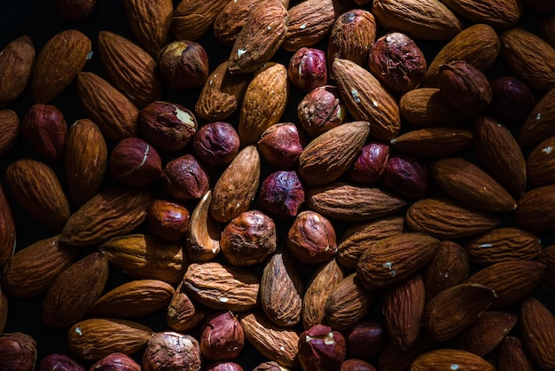 Un haz de luz cae sobre muchas nueces peladas y granos de almendras y avellanas