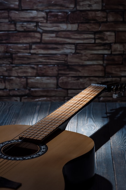 Un haz de luz ilumina una guitarra acústica tendida en la oscuridad.