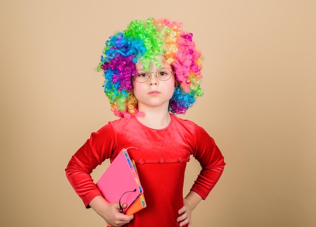 Haz que estudiar sea divertido. Infancia verdaderamente feliz. Chica linda niña juguetona usa peluca rizada de arco iris. La vida es divertida. Niña feliz niño. Día internacional del niño. Momentos felices. Adorable bebé divirtiéndose.