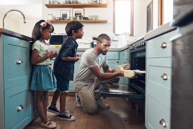 Haz que el mundo sea un lugar mejor Fotografía de un joven horneando en casa con sus dos hijos pequeños