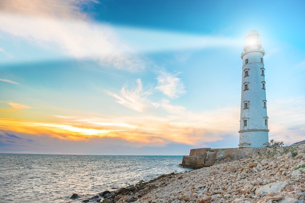 Haz del reflector del faro a través del aire del mar por la noche. Paisaje marino al atardecer