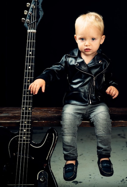 Foto haz ruido. pequeña estrella de rock. niño chico con guitarra. pequeño guitarrista con chaqueta rockera. niño estilo rockero. intérprete de música rock and roll. adorable pequeño fanático de la música. pequeño músico