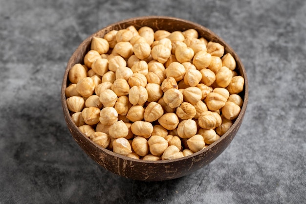 Hazelnuts asados en un cuenco sobre un fondo oscuro Nueces en un recipiente de coco de cerca