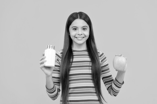 Hazte fuerte come vitaminas Niño feliz sostiene una manzana y una botella de suplemento Suplemento de manzana