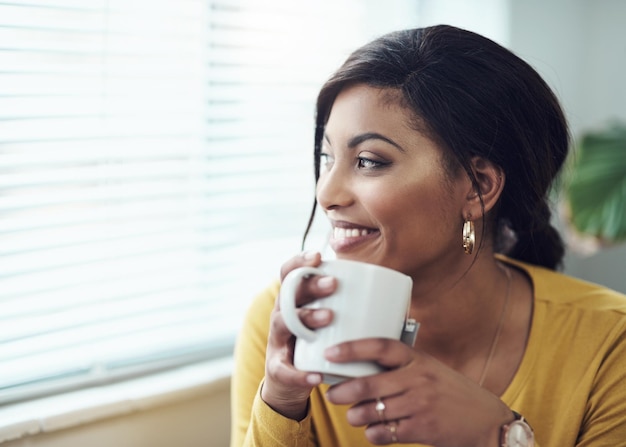 He estado esperando un fin de semana relajante Foto de una mujer joven y atractiva sentada sola en casa y bebiendo una taza de café