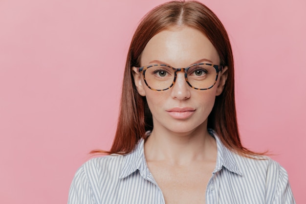 Headshot der ernsten selbstbewussten Geschäftsfrau trägt die optische Brille, gekleidet in gestreiftem Hemd