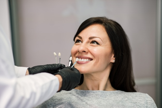 Headshot del paciente sonriente de la mujer en la oficina dental de la clínica.