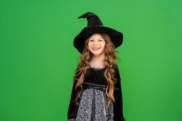 Una hechicera positiva sobre un fondo aislado, una niña pequeña con un disfraz de mago. Traje para halloween. Un hermoso disfraz para una mascarada.