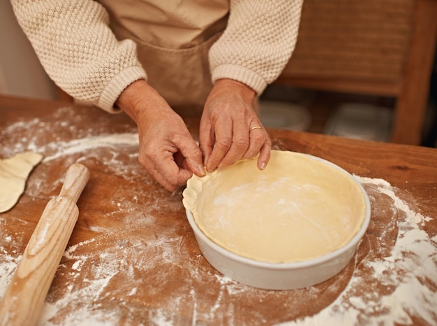 Hecho con amor Una vista recortada de manos trabajando la masa mientras hornea en una cocina