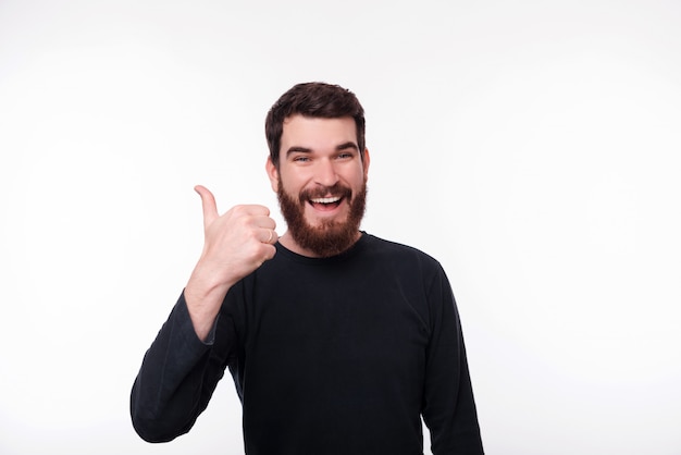 Foto hecho ! hombre barbudo alegre, independiente que muestra el pulgar hacia arriba y sonriendo a la cámara sobre fondo isoalted