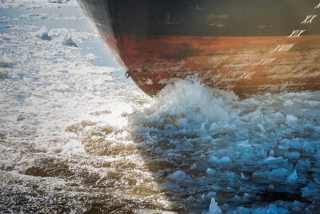 Foto heck eines schiffes, das im zeitigen frühjahr entlang eines mit eisschollen bedeckten flusses segelt