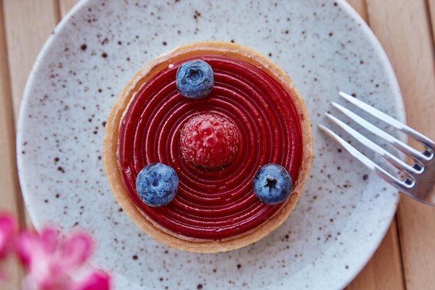 Heidelbeere und Himbeere frische Torte auf dem Teller mit Vordergrundschichten Blumen Ästhetik