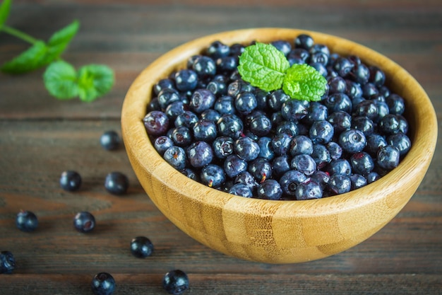 Heidelbeeren in einer Holzplatte auf dunklem Holzhintergrund Seitenansicht