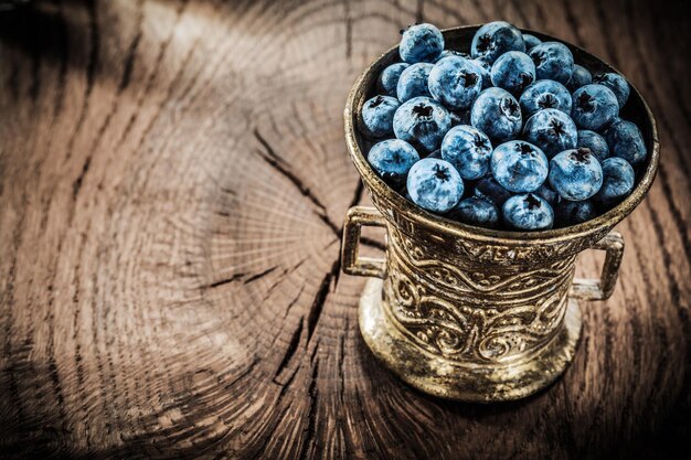 Heidelbeeren in Vintage-Metallschüssel auf Grunge-Board