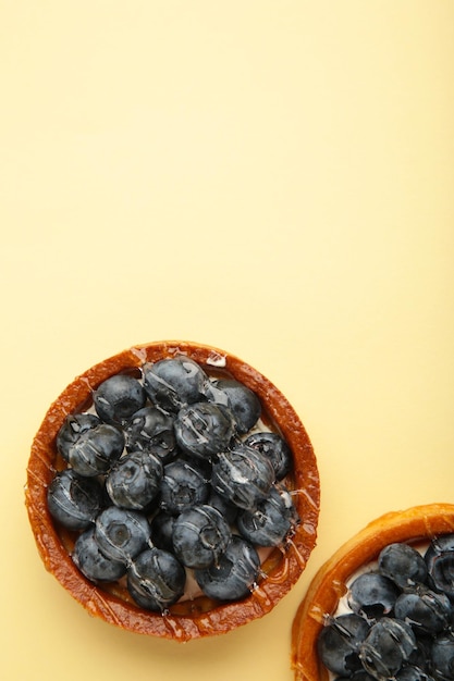 Heidelbeertörtchen auf beigem Hintergrund. Hausgemachte Torten mit schwarzen Beeren.