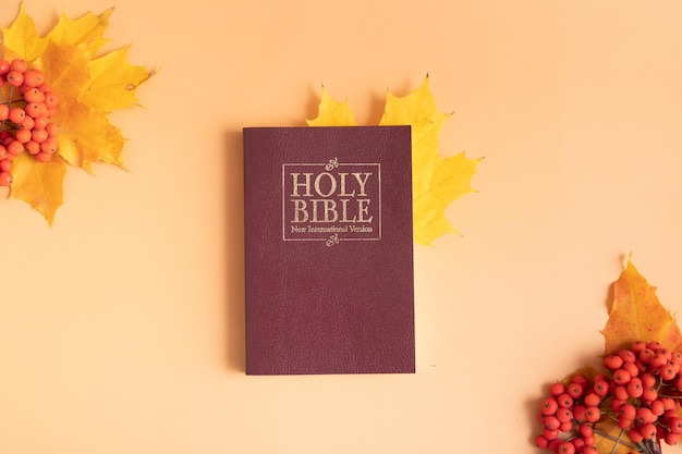 Heilige Bibel mit gelbem Blatt des Herbstes auf Draufsicht des orange Hintergrundes