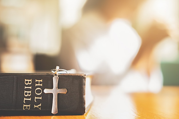 Foto heilige bibel und kreuz auf tisch mit der christlichen frau, die für besseres hofft.