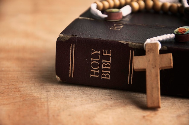 Heilige Bibel und Rosenkranz auf einem Holztisch mit anpassbarem Raum zum Hinzufügen von Ideen oder Text
