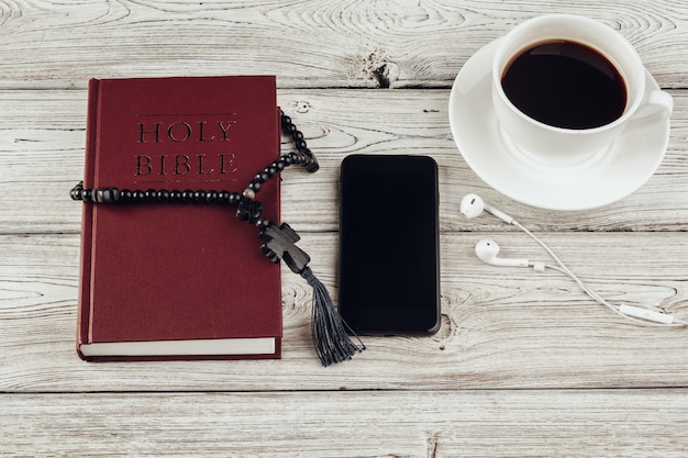 Heilige Bibel und Smartphone mit schwarzer Kaffeetasse