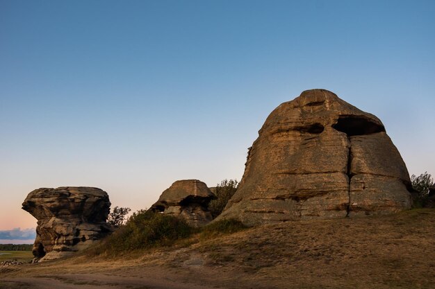 Heilige Felsenberge in Form eines Kopfes, der von der untergehenden Sonne beleuchtet wird Felsgebirgsklippe über Sonnenunterganghimmel