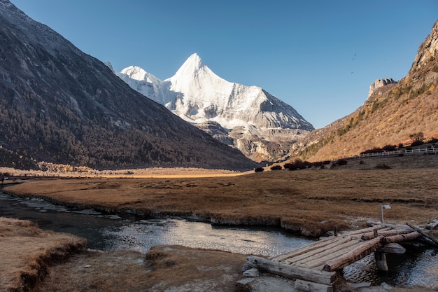 Heilige Schneegebirgs-Yangmaiyong-Reflexion über Fluss im Herbsttal auf Hochebene