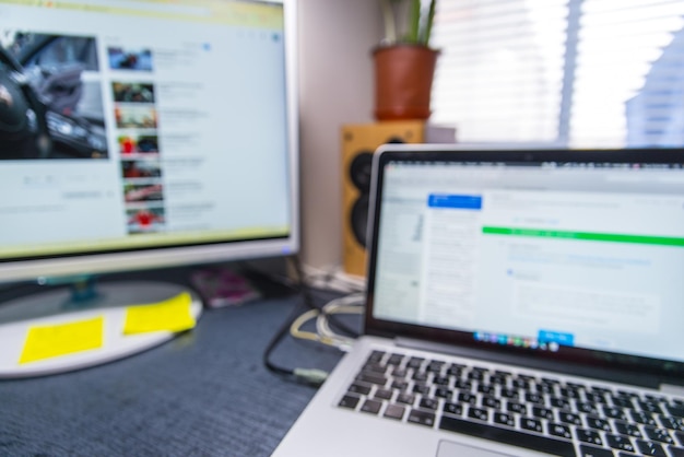 Heimarbeitsplatz. Laptop mit Monitor auf dem Tisch. unscharf