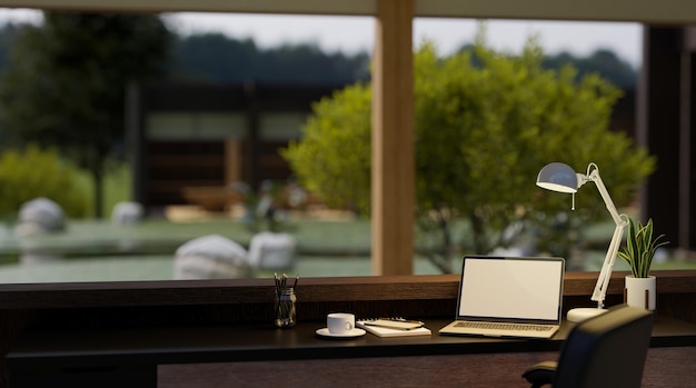 Heimarbeitsplatz mit Laptop auf dem Tisch vor verschwommenem Garten im Hintergrund