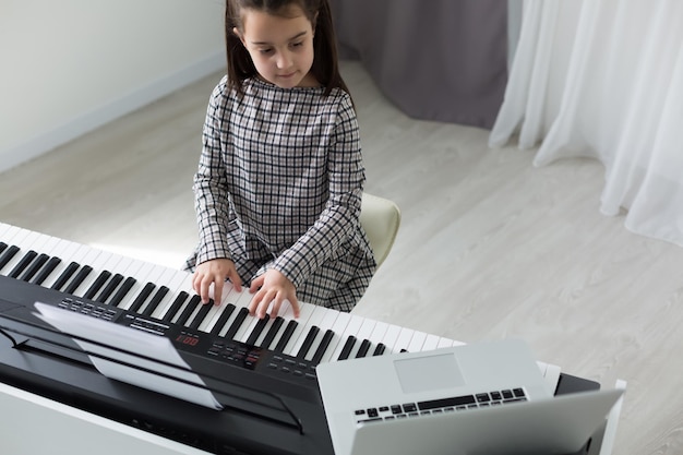 Heimunterricht über Musik für das Mädchen am Klavier. Die Idee von Aktivitäten für das Kind zu Hause während der Quarantäne. Musikkonzept