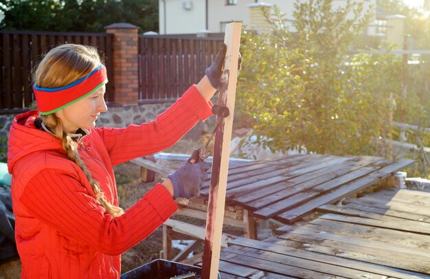 Heimwerker-Handwerkerin beim Malen von Holzbrettern im Freien